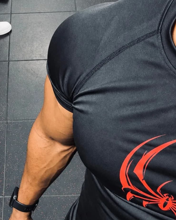 Tife in a black compression tee with a red spider print, seen from above in the gym